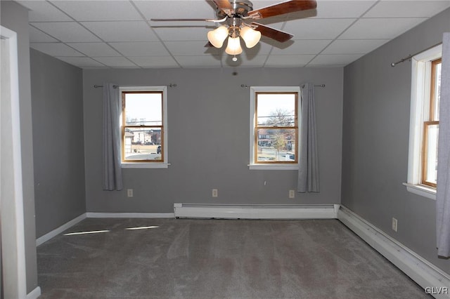 carpeted spare room with a paneled ceiling, a wealth of natural light, and a baseboard heating unit