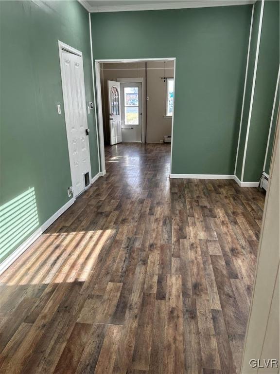 empty room with dark hardwood / wood-style floors, ornamental molding, and baseboard heating