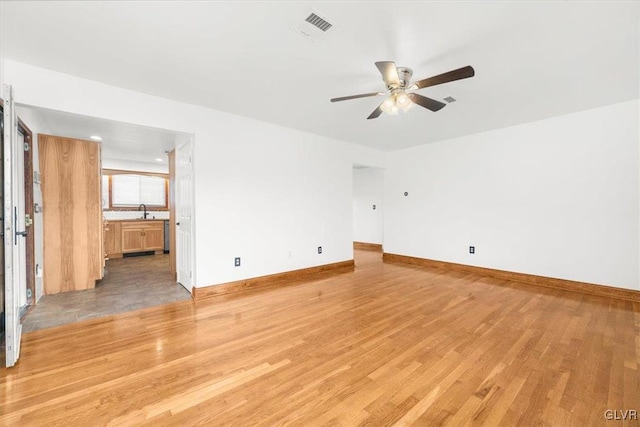 unfurnished room with light wood-type flooring, ceiling fan, and sink