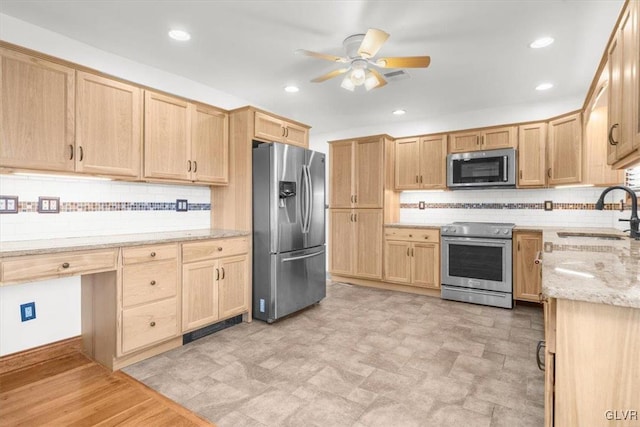 kitchen featuring ceiling fan, sink, stainless steel appliances, light stone counters, and decorative backsplash