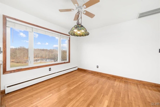 spare room with wood-type flooring, a baseboard radiator, and ceiling fan