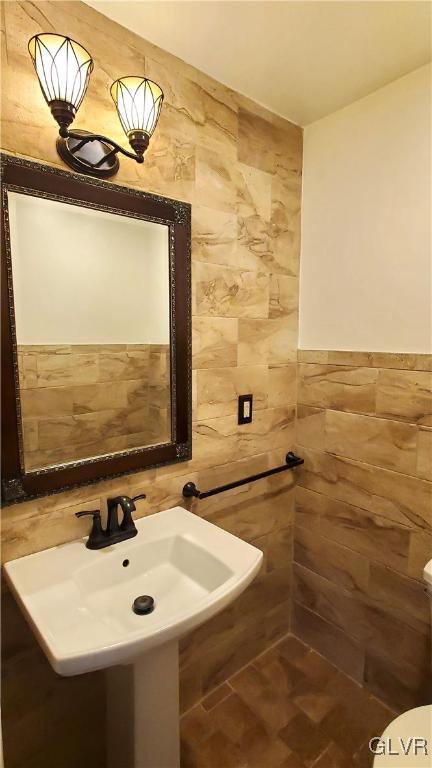 bathroom featuring sink and tile walls