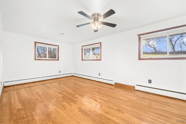 spare room featuring ceiling fan, a baseboard heating unit, and light wood-type flooring