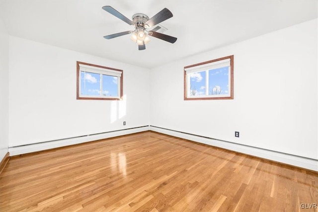 unfurnished room with a baseboard heating unit, light hardwood / wood-style floors, ceiling fan, and a healthy amount of sunlight