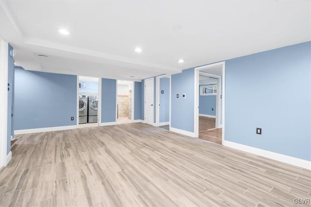 unfurnished living room with washing machine and clothes dryer and light hardwood / wood-style flooring