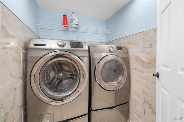 washroom featuring tile walls and washing machine and clothes dryer