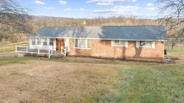 single story home featuring a wooden deck and a front yard