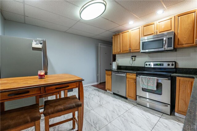 kitchen featuring a paneled ceiling, backsplash, and appliances with stainless steel finishes