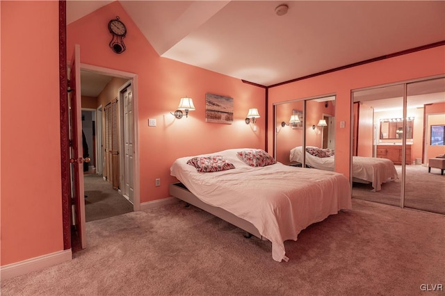 carpeted bedroom featuring multiple closets and vaulted ceiling