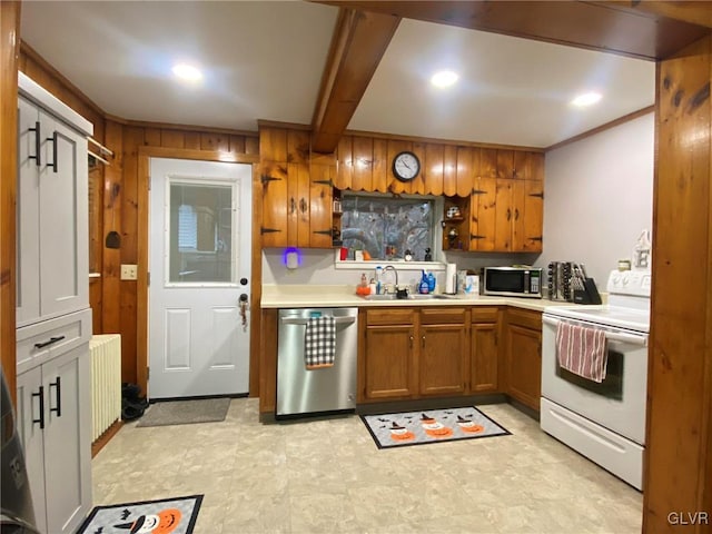 kitchen with beam ceiling, radiator, sink, wooden walls, and appliances with stainless steel finishes