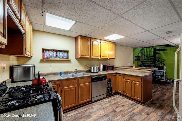 kitchen with a paneled ceiling, hardwood / wood-style floors, black appliances, sink, and kitchen peninsula