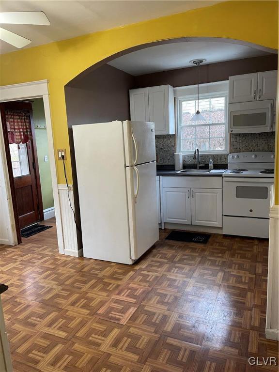 kitchen with white cabinets, white appliances, backsplash, and sink