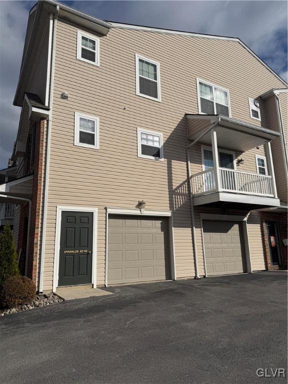 back of property with a garage and a balcony