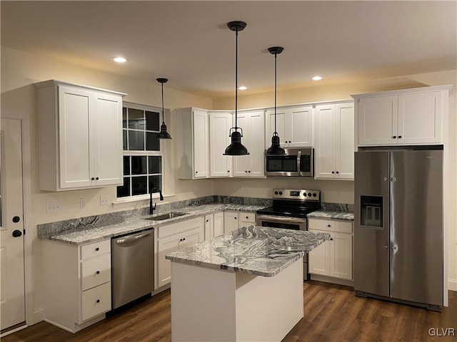 kitchen with appliances with stainless steel finishes, dark hardwood / wood-style flooring, light stone counters, sink, and decorative light fixtures