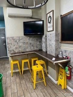 bar with hardwood / wood-style flooring, a notable chandelier, and a wall mounted AC