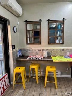 bar with a wall mounted air conditioner, a barn door, and dark wood-type flooring