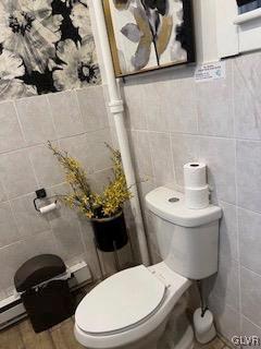 bathroom featuring a baseboard radiator, toilet, and tile walls