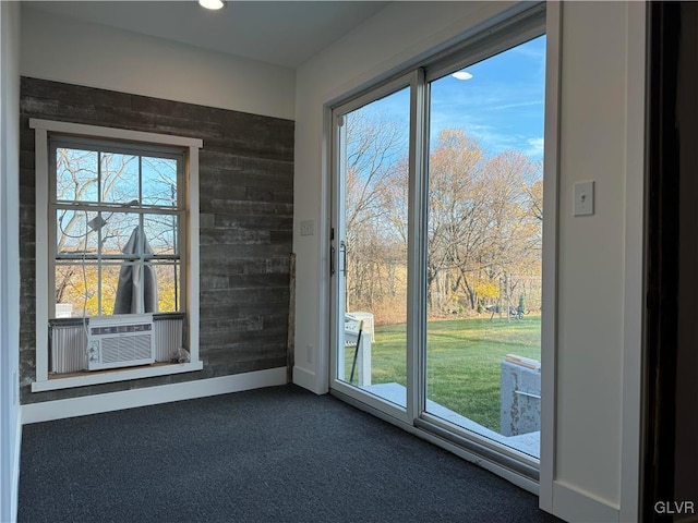 doorway to outside featuring wooden walls, cooling unit, and dark carpet