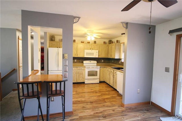 kitchen featuring white appliances, sink, light brown cabinetry, tasteful backsplash, and light hardwood / wood-style floors