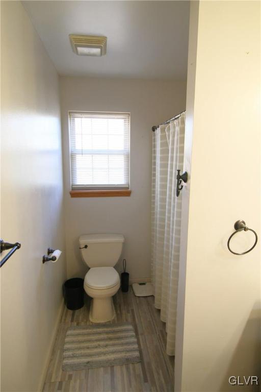 bathroom featuring walk in shower, wood-type flooring, and toilet