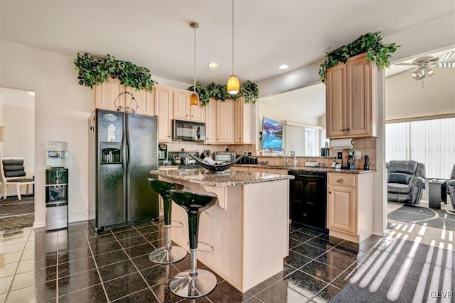 kitchen featuring pendant lighting, light brown cabinets, black appliances, light stone countertops, and a kitchen island