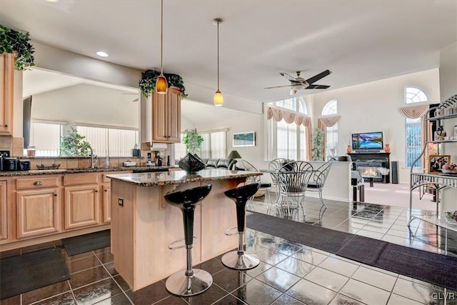 kitchen with a kitchen bar, ceiling fan, light brown cabinetry, and vaulted ceiling