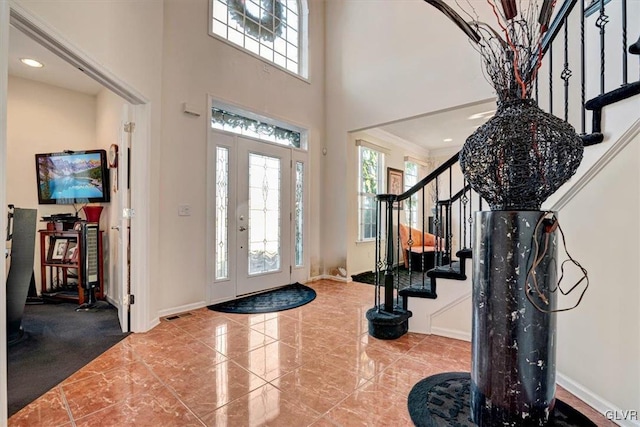 entryway with a towering ceiling and crown molding