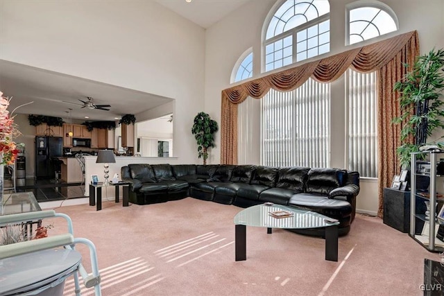 living room with light carpet, ceiling fan, and a high ceiling