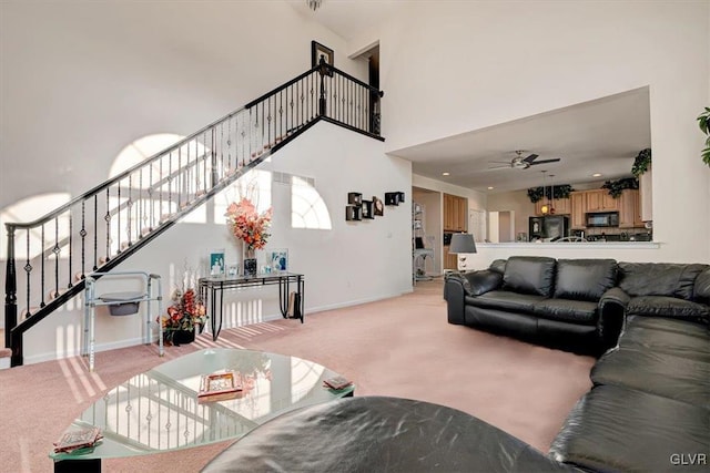 living room with light carpet, ceiling fan, and a high ceiling