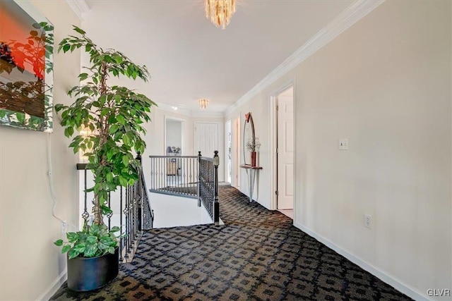 hall with dark colored carpet, ornamental molding, and a notable chandelier