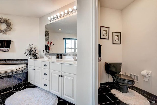 bathroom featuring tile patterned flooring, vanity, toilet, and tiled bath