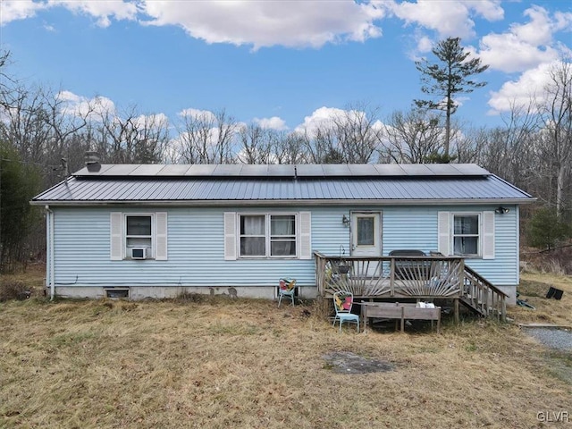 back of property featuring solar panels, cooling unit, a deck, and a yard