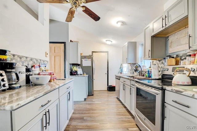 kitchen with ceiling fan, tasteful backsplash, stainless steel appliances, and vaulted ceiling