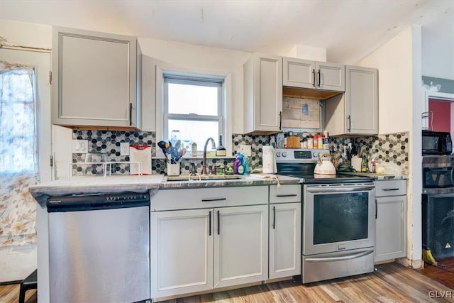 kitchen featuring gray cabinets, decorative backsplash, and stainless steel appliances