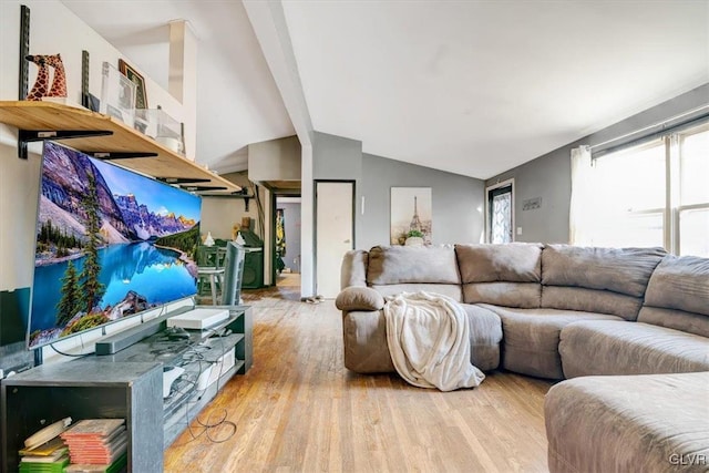 living room with vaulted ceiling with beams and light hardwood / wood-style flooring