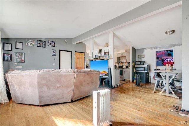 living room featuring vaulted ceiling with beams and light hardwood / wood-style floors