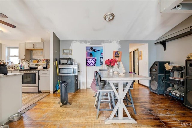 dining space with ceiling fan, wood-type flooring, sink, and lofted ceiling