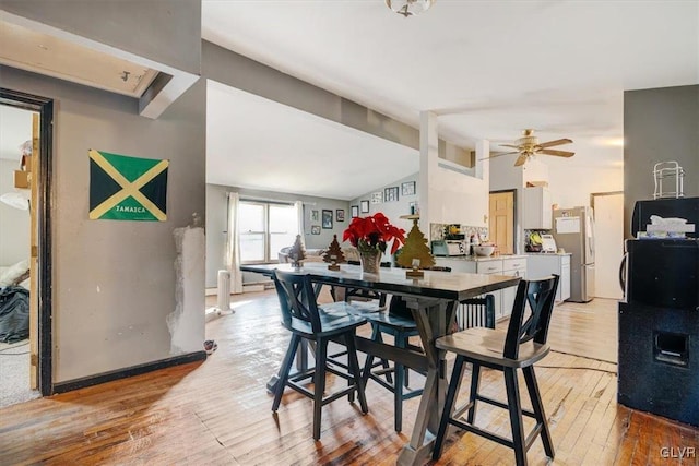 dining room featuring ceiling fan, vaulted ceiling, and light wood-type flooring