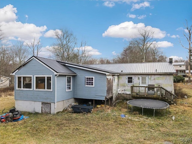 back of house with a lawn, a deck, and a trampoline