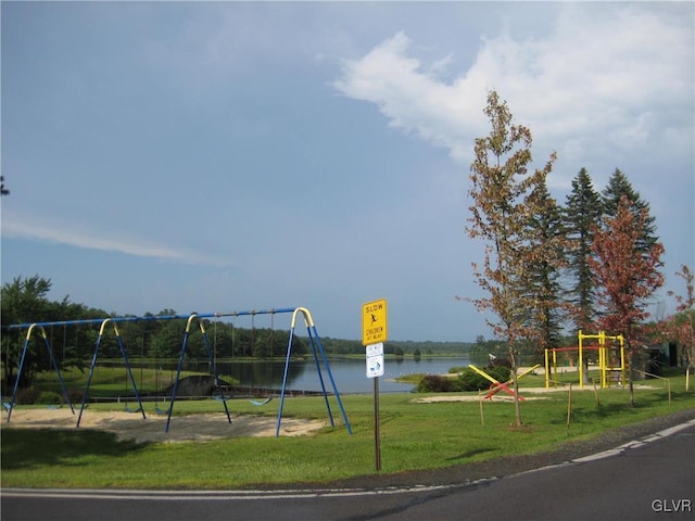 view of jungle gym with a lawn and a water view