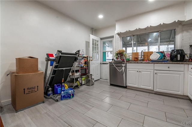 kitchen featuring dishwasher, white cabinetry, dark stone counters, and sink