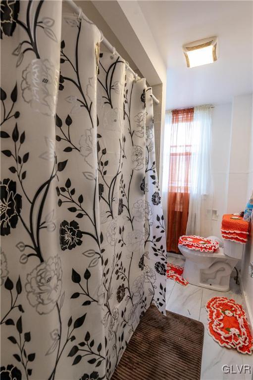 bathroom featuring a shower with curtain and toilet