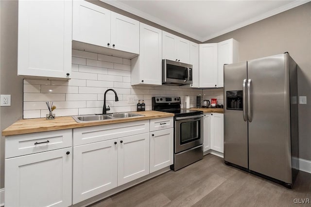 kitchen featuring wood counters, sink, decorative backsplash, appliances with stainless steel finishes, and white cabinetry