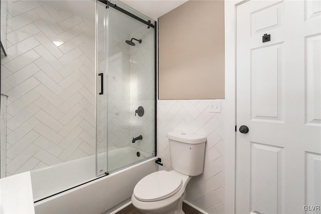 bathroom with toilet, shower / bath combination with glass door, and tile walls