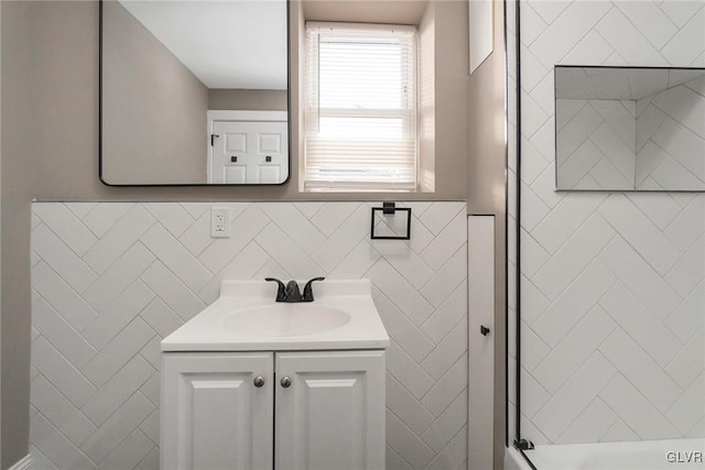 bathroom featuring a shower, vanity, and tile walls