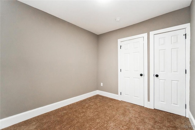 unfurnished bedroom featuring carpet and multiple closets