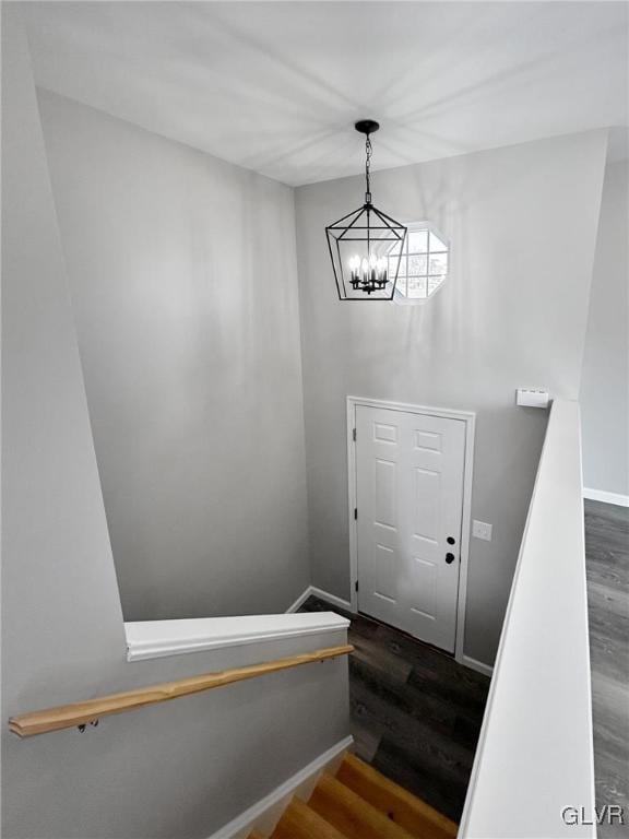 stairs with hardwood / wood-style floors and an inviting chandelier