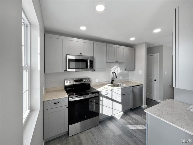 kitchen with gray cabinetry, sink, stainless steel appliances, and dark wood-type flooring