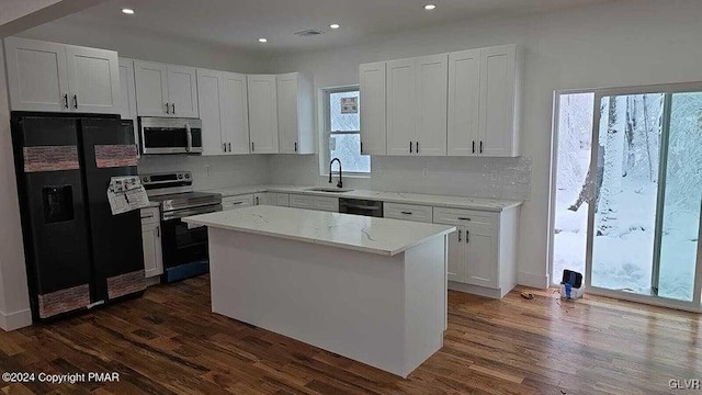 kitchen featuring white cabinetry, a healthy amount of sunlight, a center island, and black appliances