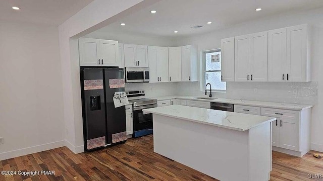 kitchen featuring appliances with stainless steel finishes, white cabinetry, a kitchen island, and light stone counters